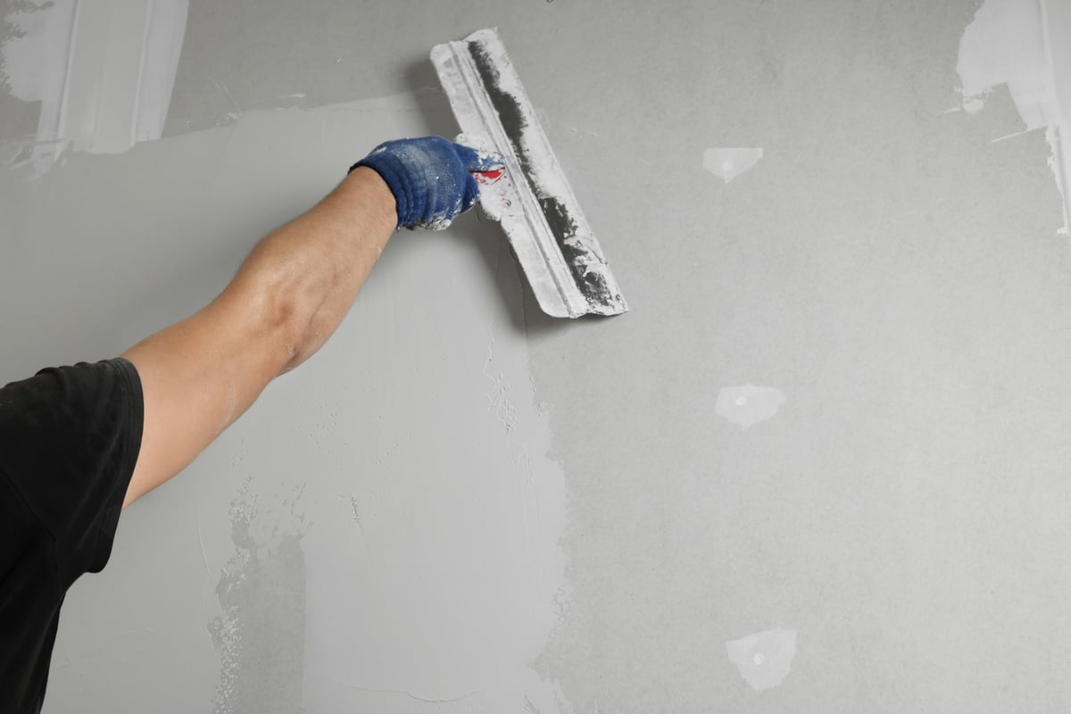 Professional plasterer finishing a wall with a putty knife — quality drywall finishing