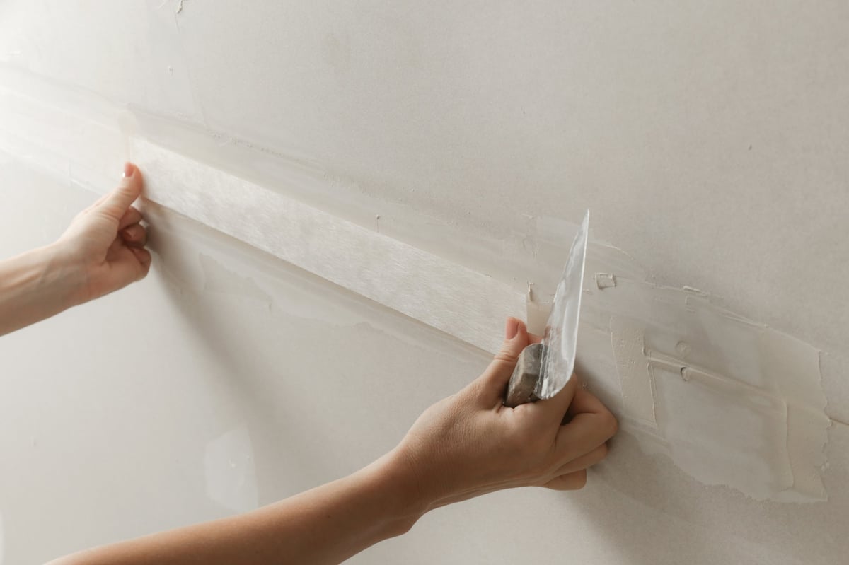 Worker taping and mudding drywall joints — professional tape and jointing in progress